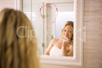 Beautiful blonde looking a big heart on mirror