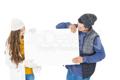 Happy couple in winter clothes holding a poster