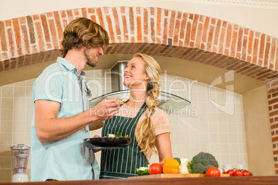 Handsome man making his girlfriend taste the preparation