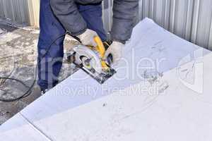 Electric hand tool in the hands of the worker, cutting sheet met