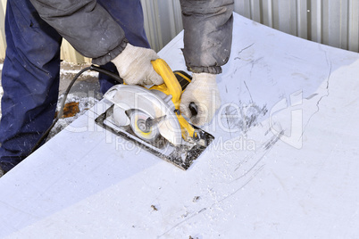 Electric hand tool in the hands of the worker, cutting sheet met