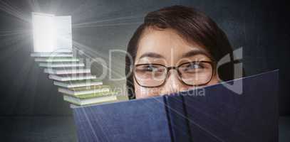 Composite image of pretty student hiding face behind a book