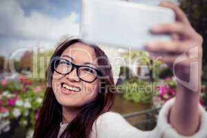 Composite image of smiling asian woman taking selfie