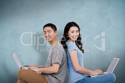 Composite image of portrait of young happy couple using laptop w