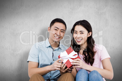 Composite image of happy couple holding gift box