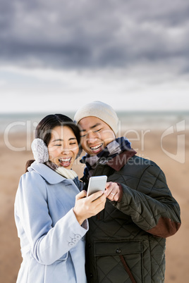 Composite image of cheerful couple looking at the smart phone