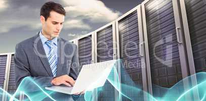 Composite image of businessman using laptop with colleagues behi