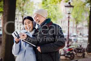 Composite image of couple laughing at their pictures taken on sm