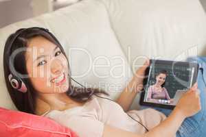 Composite image of girl using her tablet pc on the sofa and list
