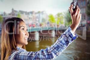 Composite image of smiling asian woman taking picture with camer