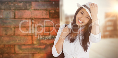 Composite image of woman with casual clothes holding her hat