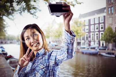 Composite image of smiling asian woman taking picture with camer