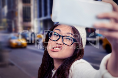 Composite image of asian woman making faces and taking selfie