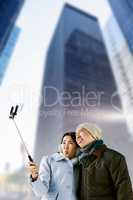 Composite image of playful couple taking selfie against building