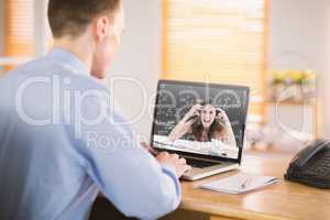 Composite image of businessman working on his laptop