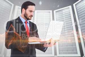 Composite image of focused businessman using his laptop