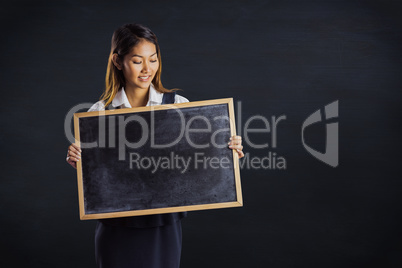 Composite image of smiling businesswoman holding a blackboard