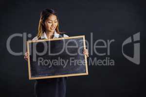 Composite image of smiling businesswoman holding a blackboard