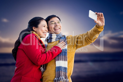 Composite image of older asian couple on balcony taking selfie