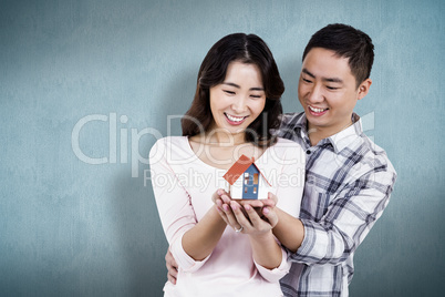 Composite image of happy couple holding a model house