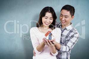 Composite image of happy couple holding a model house