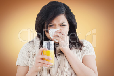 Woman holding a glass of orange juice while sneezing