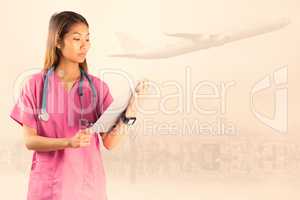 Composite image of asian nurse with stethoscope looking at the c