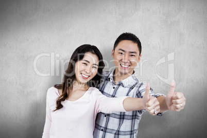 Composite image of couple showing thumbs up while standing