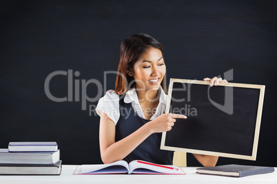 Composite image of smiling businesswoman pointing a blackboard