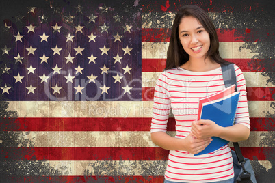 Composite image of college girl holding books with blurred stude