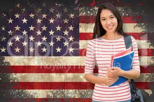 Composite image of college girl holding books with blurred stude