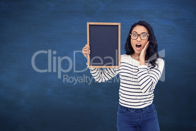 Composite image of surprised asian woman holding blackboard