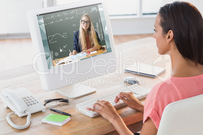 Composite image of businesswoman using computer at desk in creat