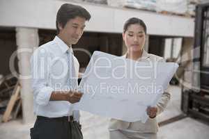 Composite image of estate agent and buyer looking at blueprint