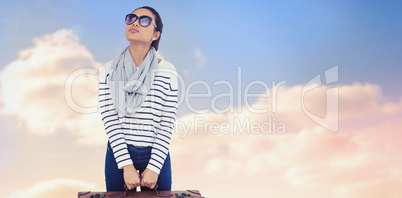 Composite image of asian woman with luggage looking up