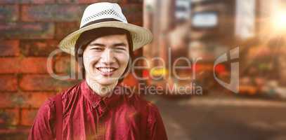 Composite image of smiling hipster with a straw hat