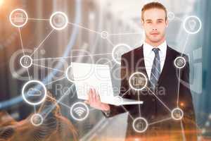 Composite image of serious businessman posing and holding laptop