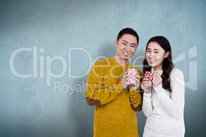 Composite image of portrait of happy young couple holding cups