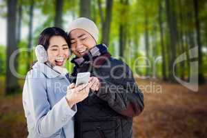 Composite image of cheerful couple looking at the smart phone