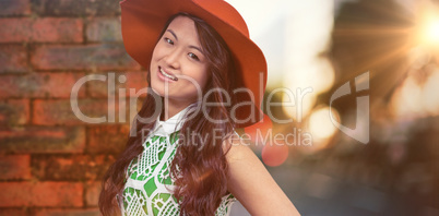 Composite image of asian woman with hat posing for camera