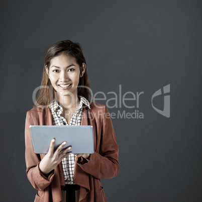 Composite image of smiling businesswoman using a tablet