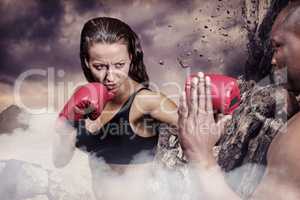 Composite image of female boxer practicing with trainer