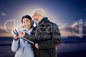 Composite image of couple laughing at their pictures taken on sm