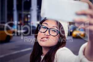 Composite image of asian woman making faces and taking selfie