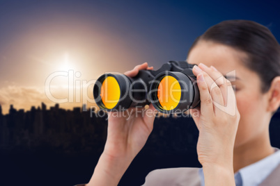 Composite image of brunette businesswoman looking through binocu