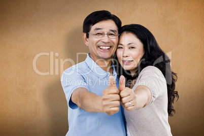 Composite image of smiling couple with thumbs up