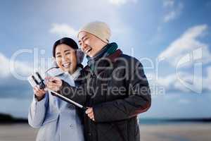 Composite image of couple laughing at their pictures taken on sm