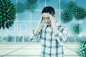 Composite image of asian man getting a headache