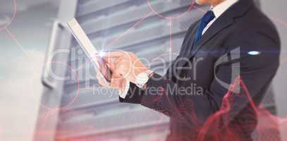 Composite image of businessman in suit using digital tablet