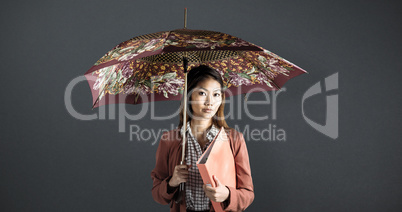Composite image of businesswoman with an umbrella holding a bind